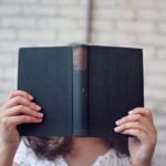 selective focus photography of woman holding book